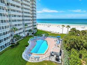 Um hotel com piscina, vista para a praia e um edifício alto.