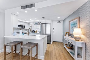 A modern kitchen with white cabinetry, a central island, and bar stools.