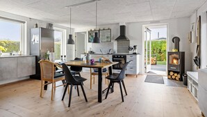 A modern kitchen with a dining area, a large window, and a wood-burning stove. - 1 bedroom gorgeous home in Bogense (Bogense)