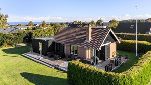 A modern house with a sloped roof, a deck, and a view of the sea. - 1 bedroom gorgeous home in Bogense (Bogense)