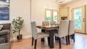A dining area with a wooden table and six chairs, a potted plant, and a painting on the wall. - Canyon Treehouse (San Diego)