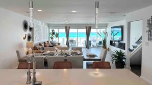 A spacious living area with a dining table, sofas, and a TV mounted on the wall. - Destin Beachfront Oasis (Miramar Beach)