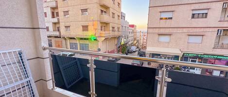 Un balcon avec une balustrade en métal, une vue sur les bâtiments voisins et une enseigne indiquant « SERVICES D’ÉCLAIRAGE MAJESTRO ».