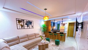 Uma sala de estar moderna com um sofá, uma mesa de centro e um espaço bar com banquetas.