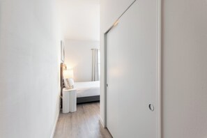 A narrow hallway leading to a bedroom with a bed, bedside tables, and a lamp. - Whimsy by Avantstay Pool 30min to Disney (Davenport)