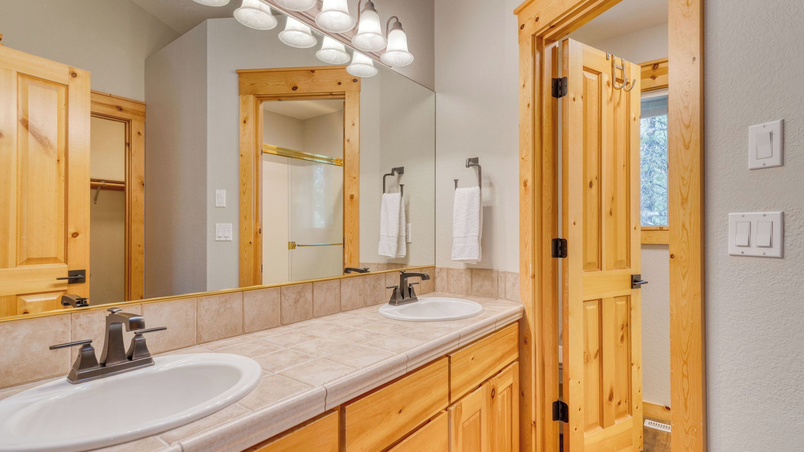 Un baño con dos lavamanos, un espejo grande y muebles de madera.