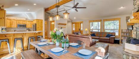 A spacious kitchen with wooden cabinets, a dining table set for four, and a cozy living area with a sofa and fireplace.