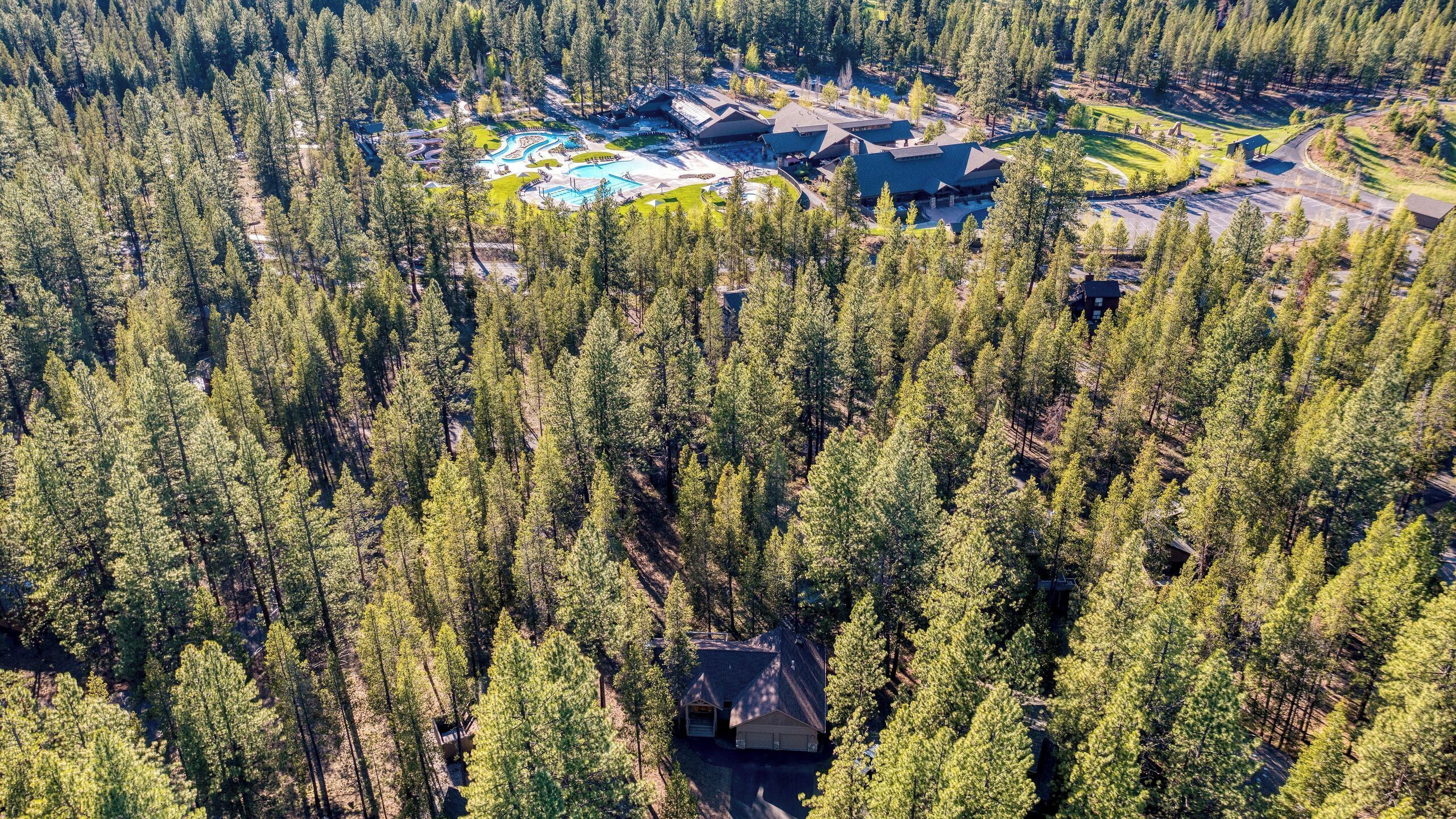 Oversigtsbillede af et resort med flere bygninger, en swimmingpool og en tæt skov omkring ejendommen.