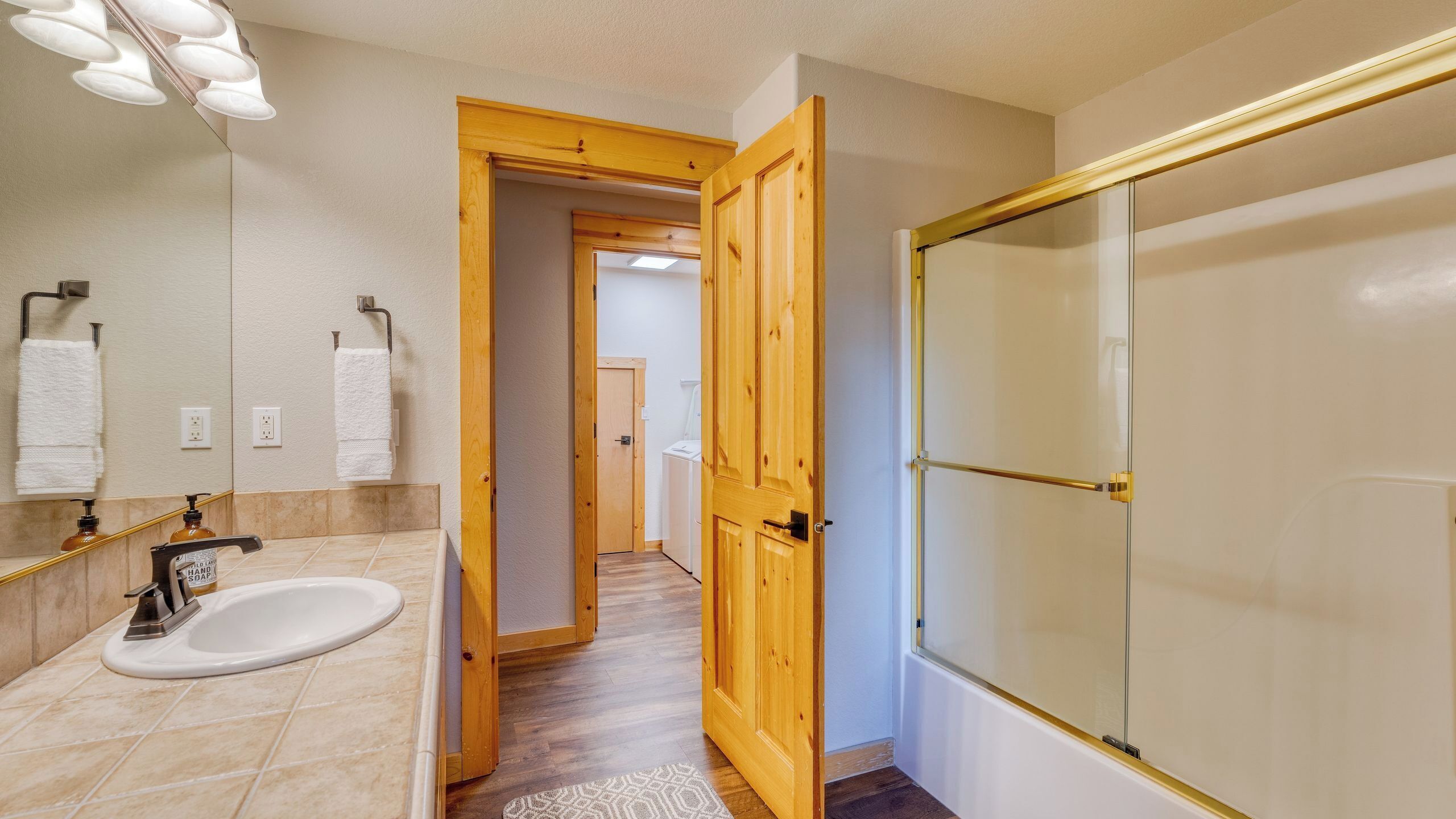 A bathroom with a sink, mirror, and shower.