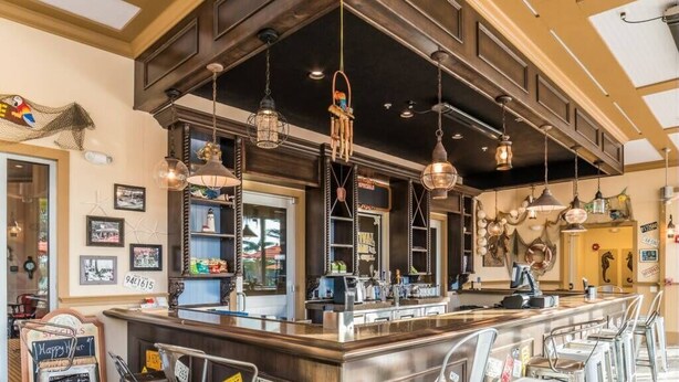 A bar area with a counter, bar stools, and hanging pendant lights.