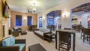 A spacious indoor area with wicker furniture, a fireplace, and a dining area with tables and chairs. - DLuxx Resort Villa w/ Pool & Lazy River 8965 (Kissimmee)