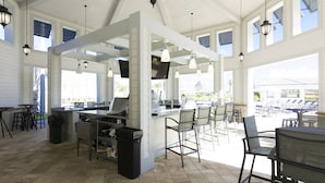 A spacious indoor area with a bar, seating, and large windows.