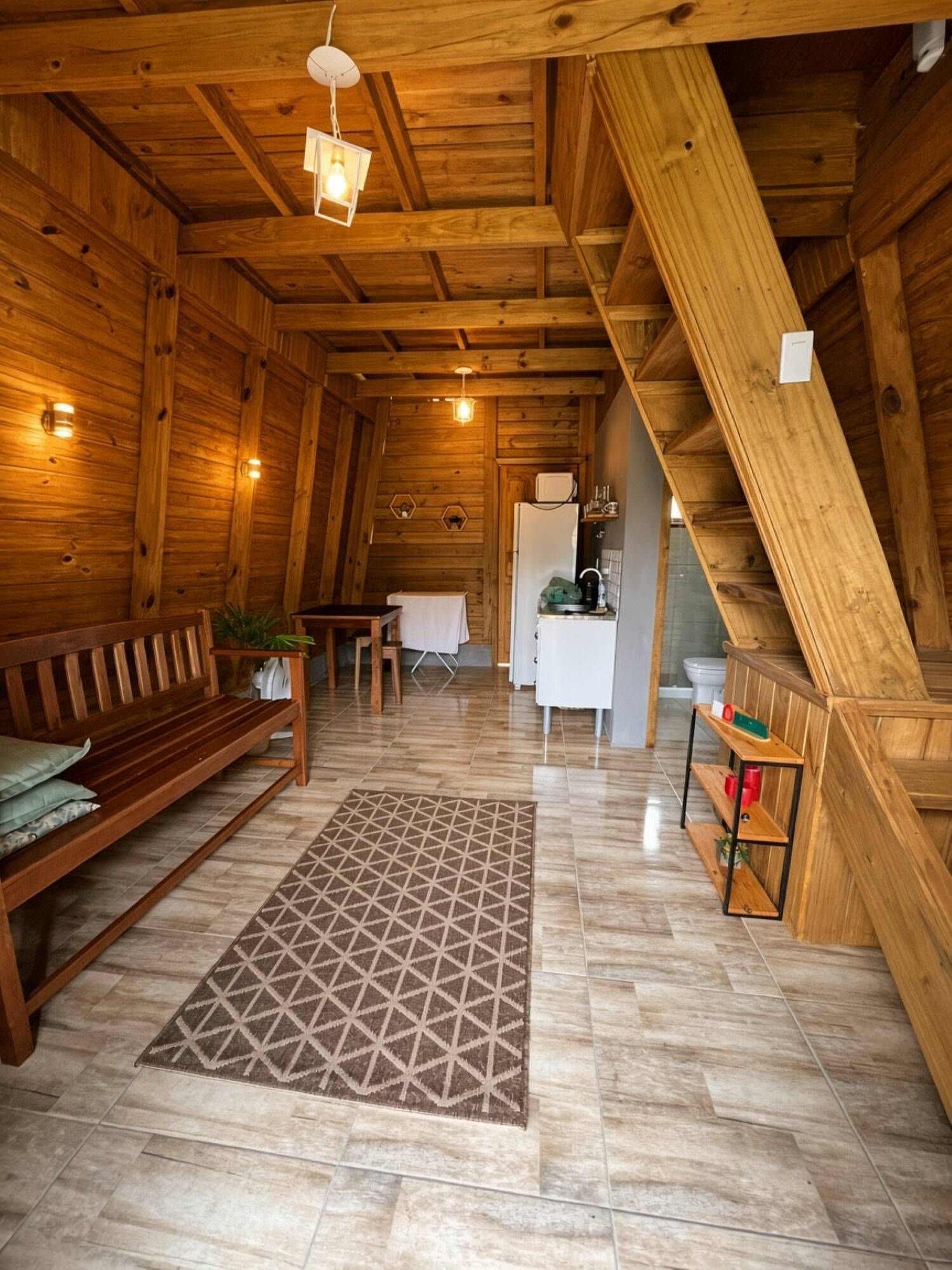 Ein Holzinnenraum mit einer Couch, einem Esstisch, einer Küchenzeile und einer Treppe.