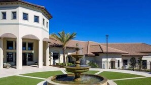 A building with a circular fountain in the center, surrounded by a well-maintained lawn. - Top Oasis Vacation Home 12 Miles From Disney 1405 (Davenport)
