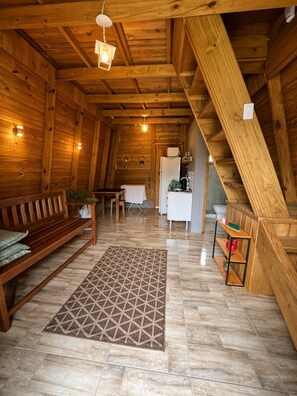 A wooden interior with a sofa, dining table, kitchen area, and a staircase. - N5 - Chalé 2 Quartos Angra dos Reis (Angra dos Reis)