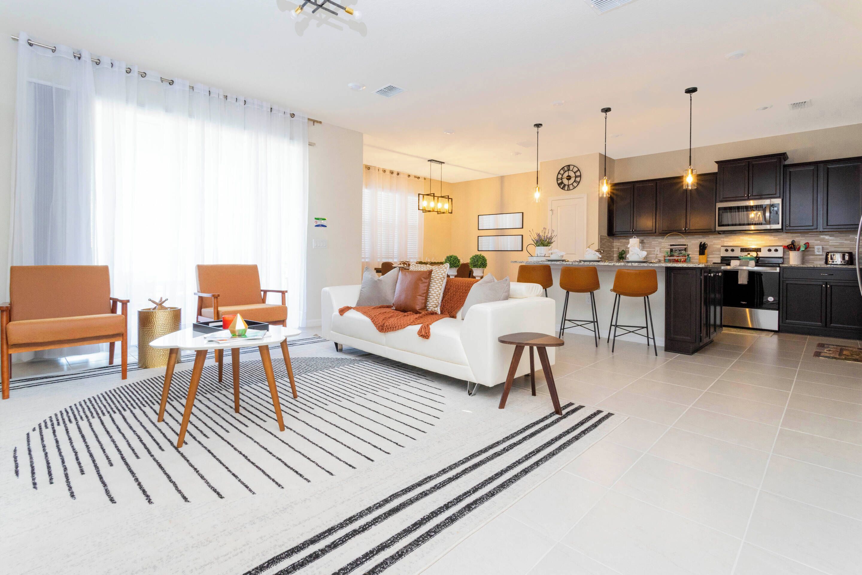 A modern living room with a white sofa, a coffee table, and a dining area with bar stools.