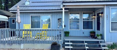 A house with a porch, yellow chairs, a covered area, and a number 401 sign.