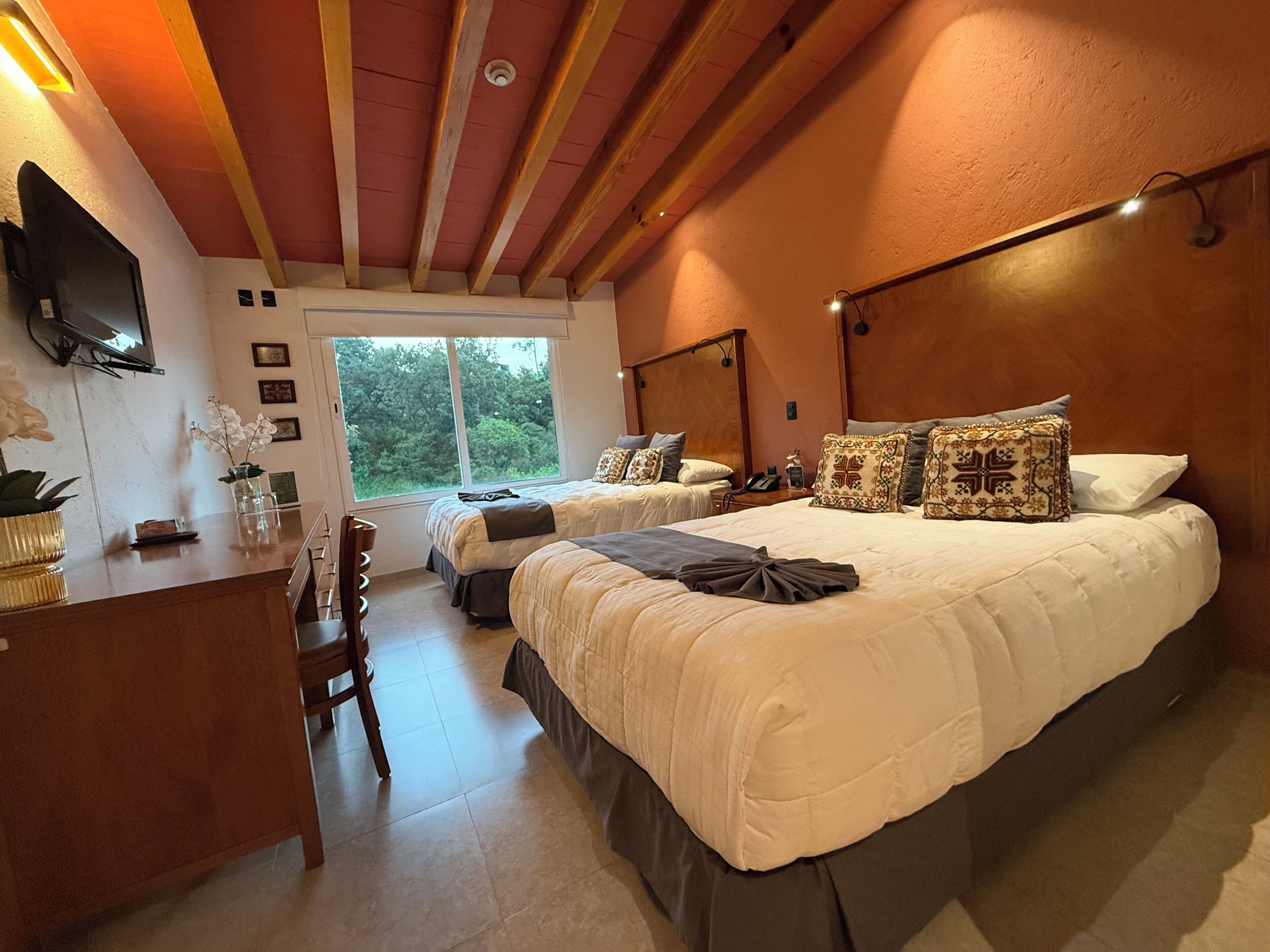 A bedroom with two beds, a desk, and a TV.