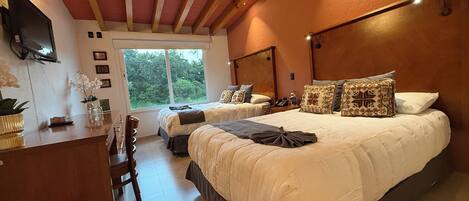 A bedroom with two beds, a desk, and a TV.
