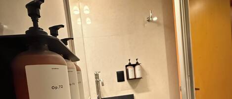 A modern bathroom with a black sink, a mirror, and two bottles of shampoo labeled 'Op.72'.