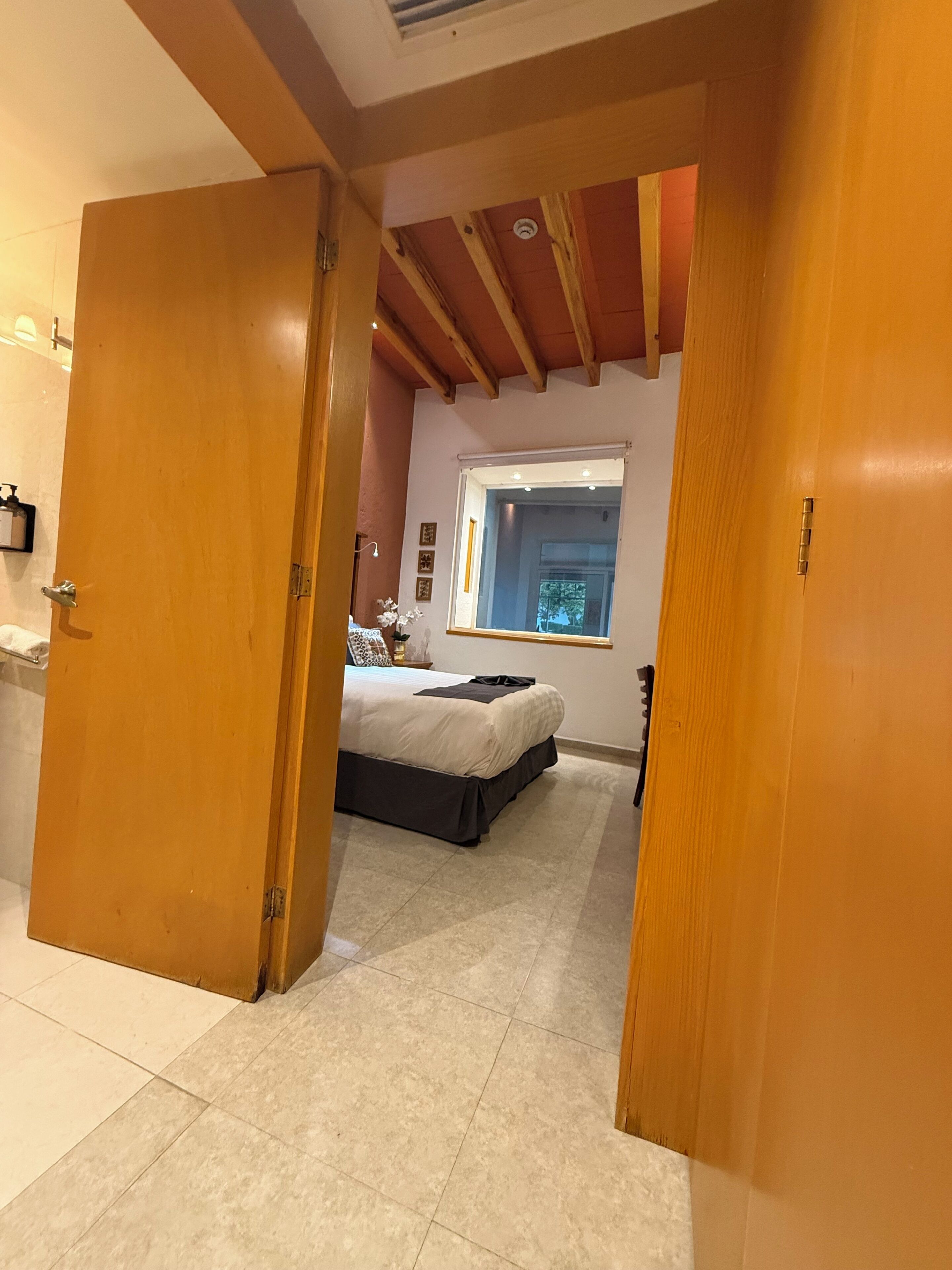 Une chambre à coucher avec un lit, une fenêtre et une porte donnant sur une autre pièce.