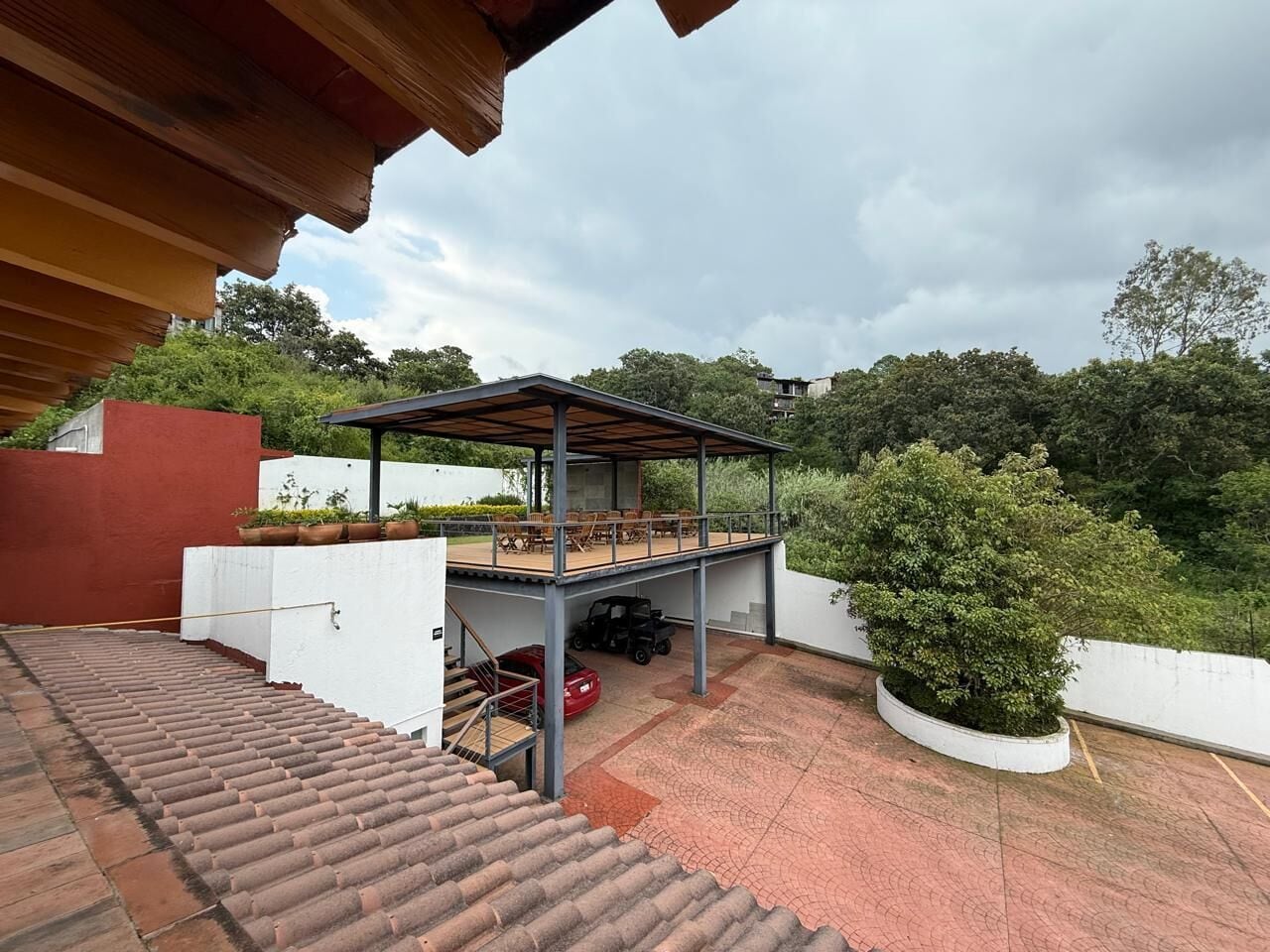 Un espacio al aire libre cubierto con un patio, un porche cubierto y una escalera que sube a un nivel superior.