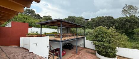 Un espacio al aire libre cubierto con un patio, un porche cubierto y una escalera que sube a un nivel superior.