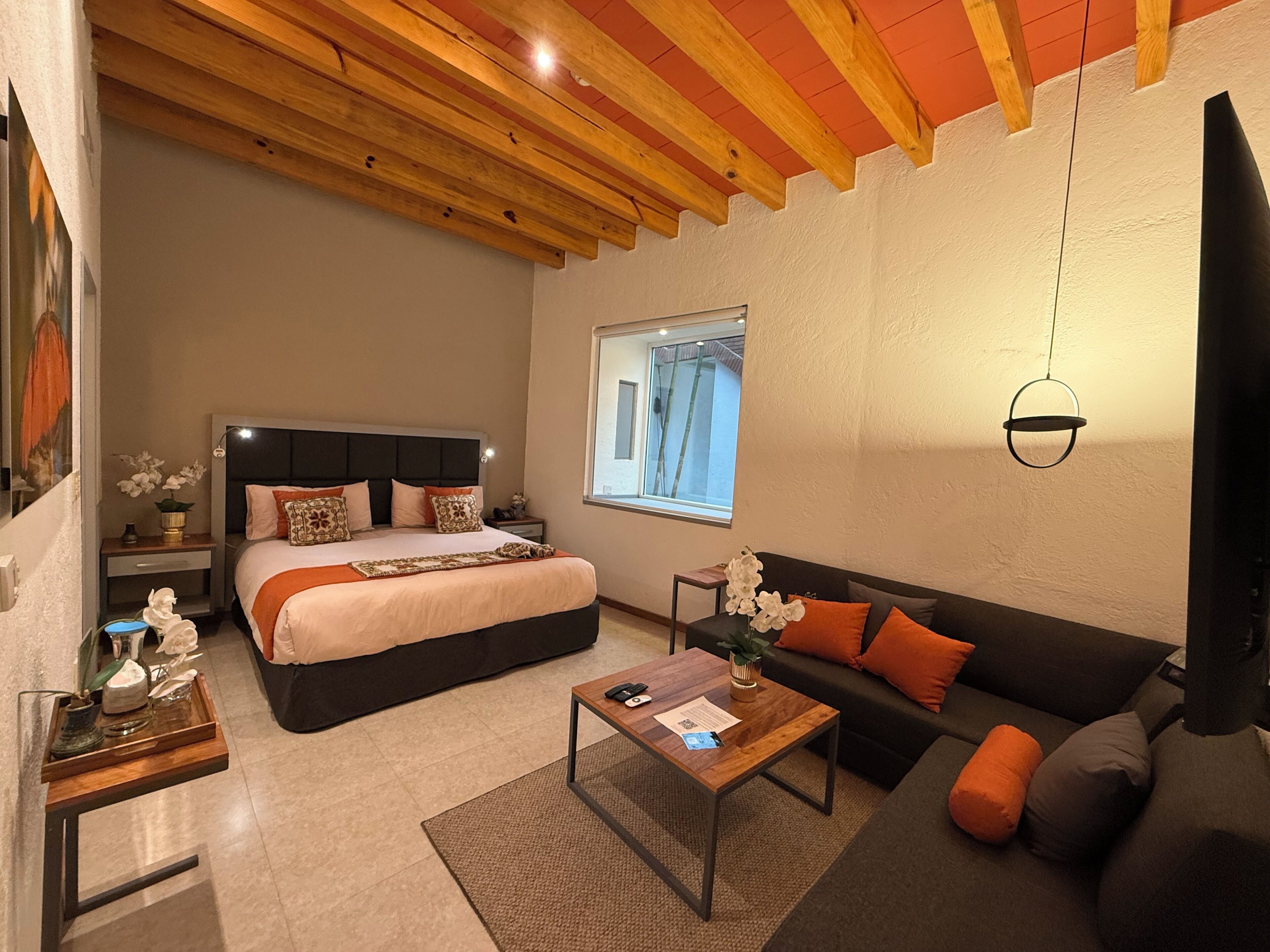 Ein modernes Schlafzimmer mit einem großen Bett, einer Couch, einem Couchtisch und einem Fenster mit Blick.
