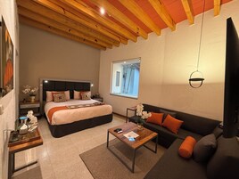 Une chambre moderne avec un grand lit, un canapé, une table basse et une fenêtre donnant sur un beau paysage.