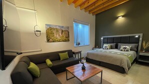 Un dormitorio moderno con cama, sofá, mesa de centro y un cuadro en la pared.