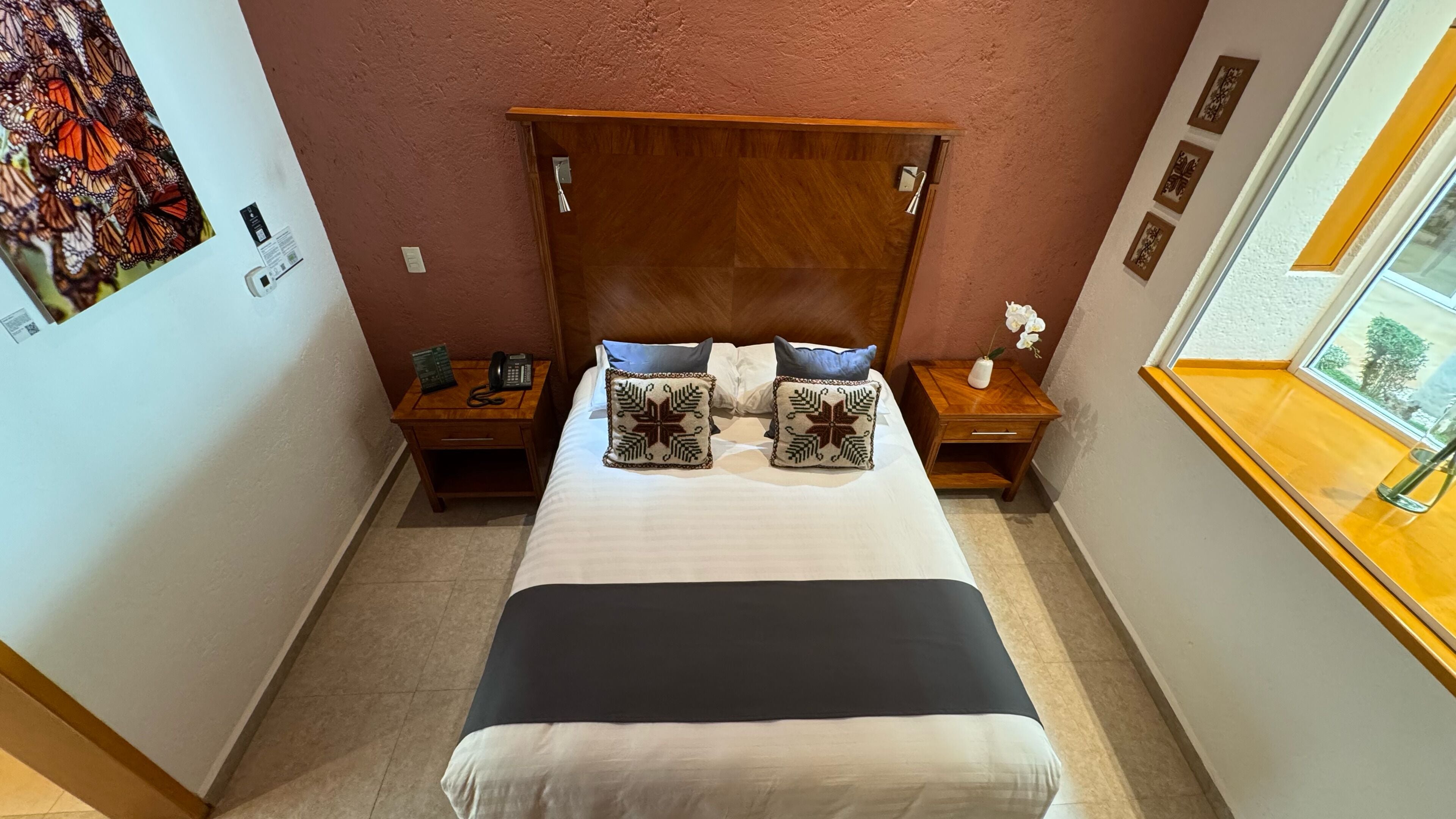 A bedroom with a large bed, two bedside tables, and a window with a view.