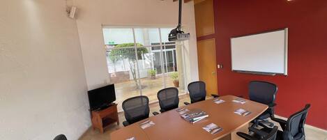 A conference room with a large table, black office chairs, a whiteboard, and a projector.