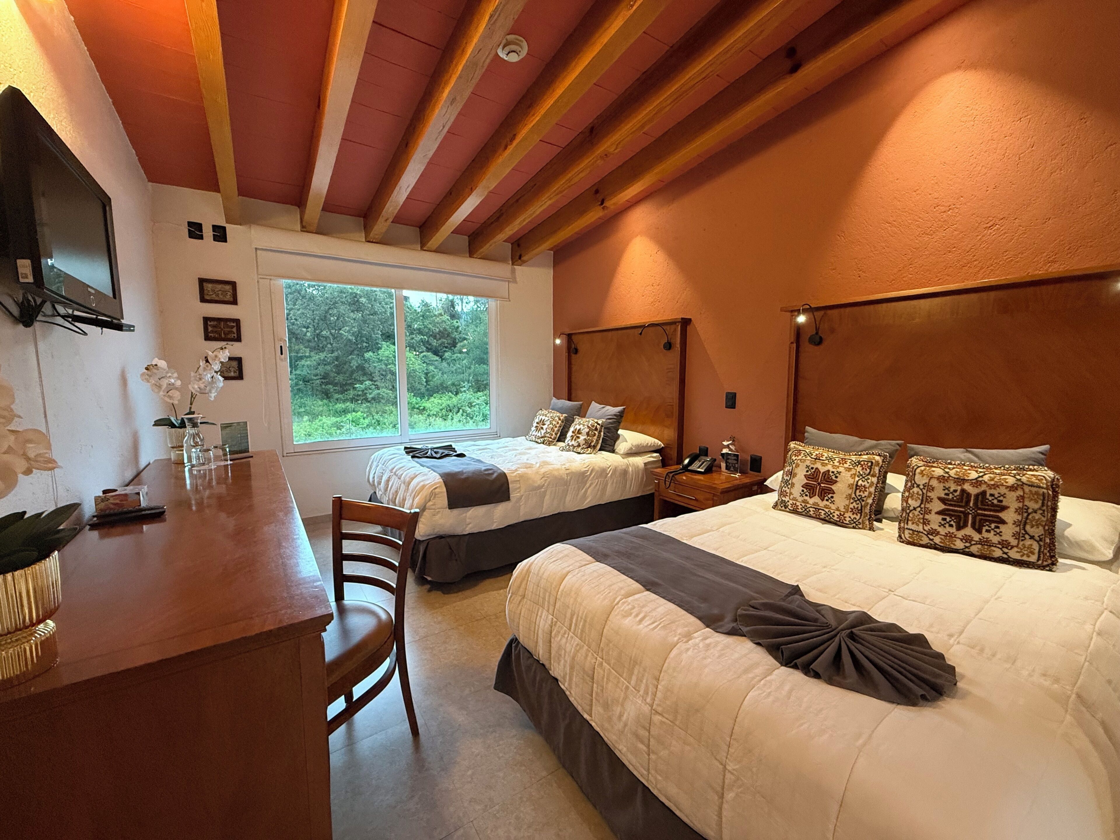 A hotel room with two beds, a desk, and a chair.