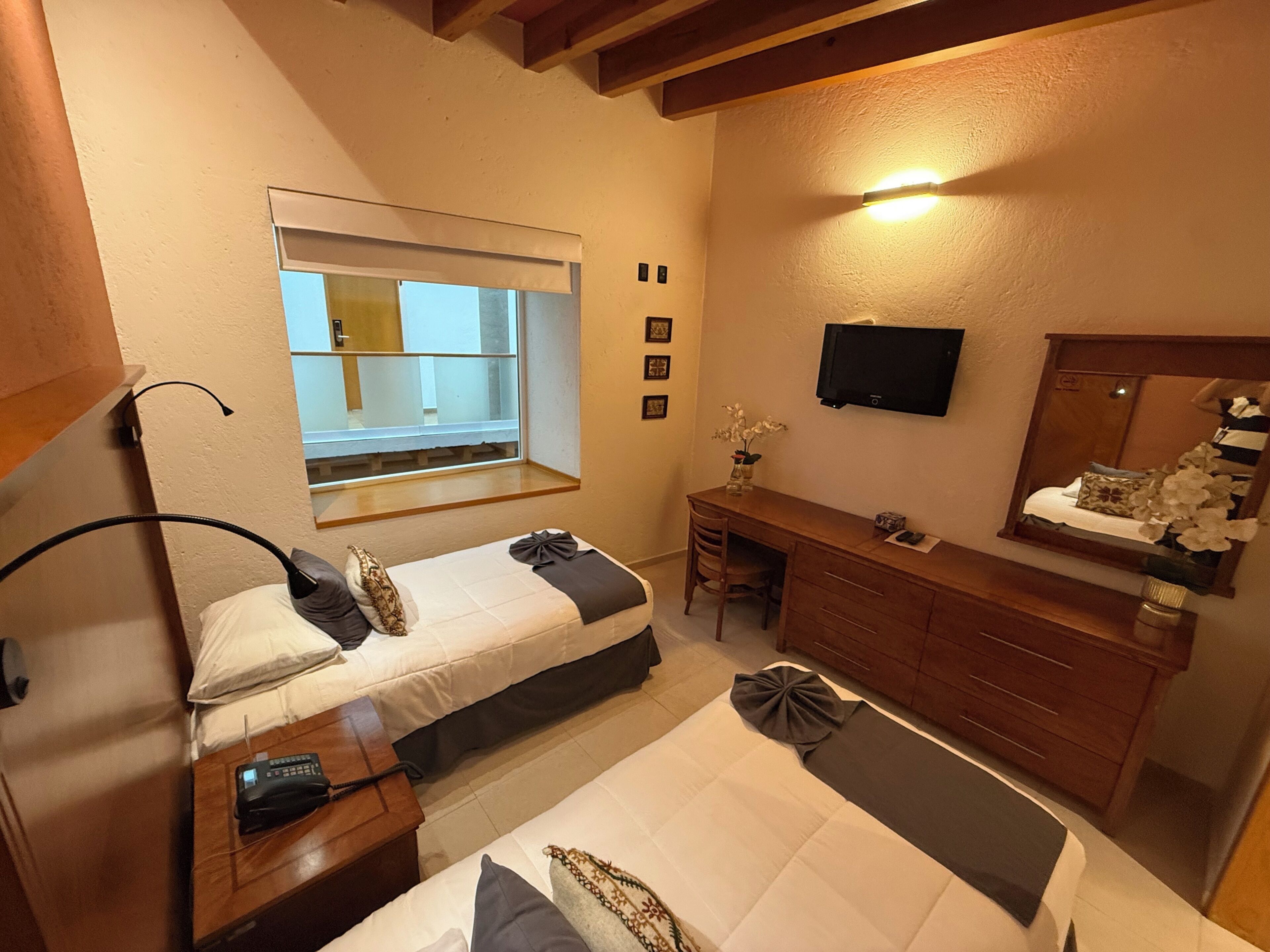 Un dormitorio con dos camas, un escritorio, una silla, un televisor y una ventana con vistas.
