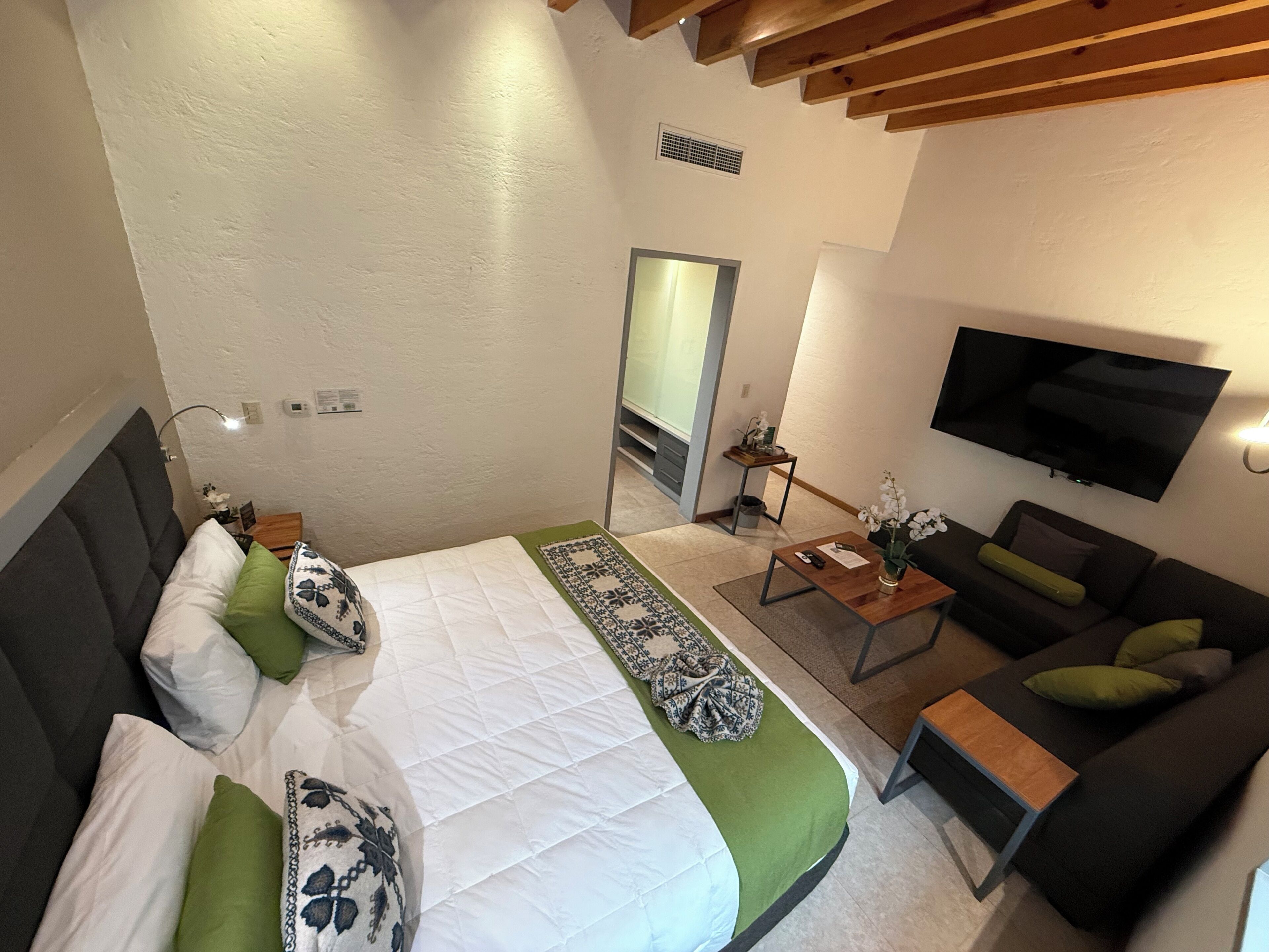 Una habitación de hotel con cama, sofá, televisor y una mesita.