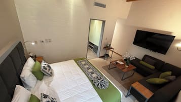 A hotel room with a bed, a sofa, a TV, and a small table.