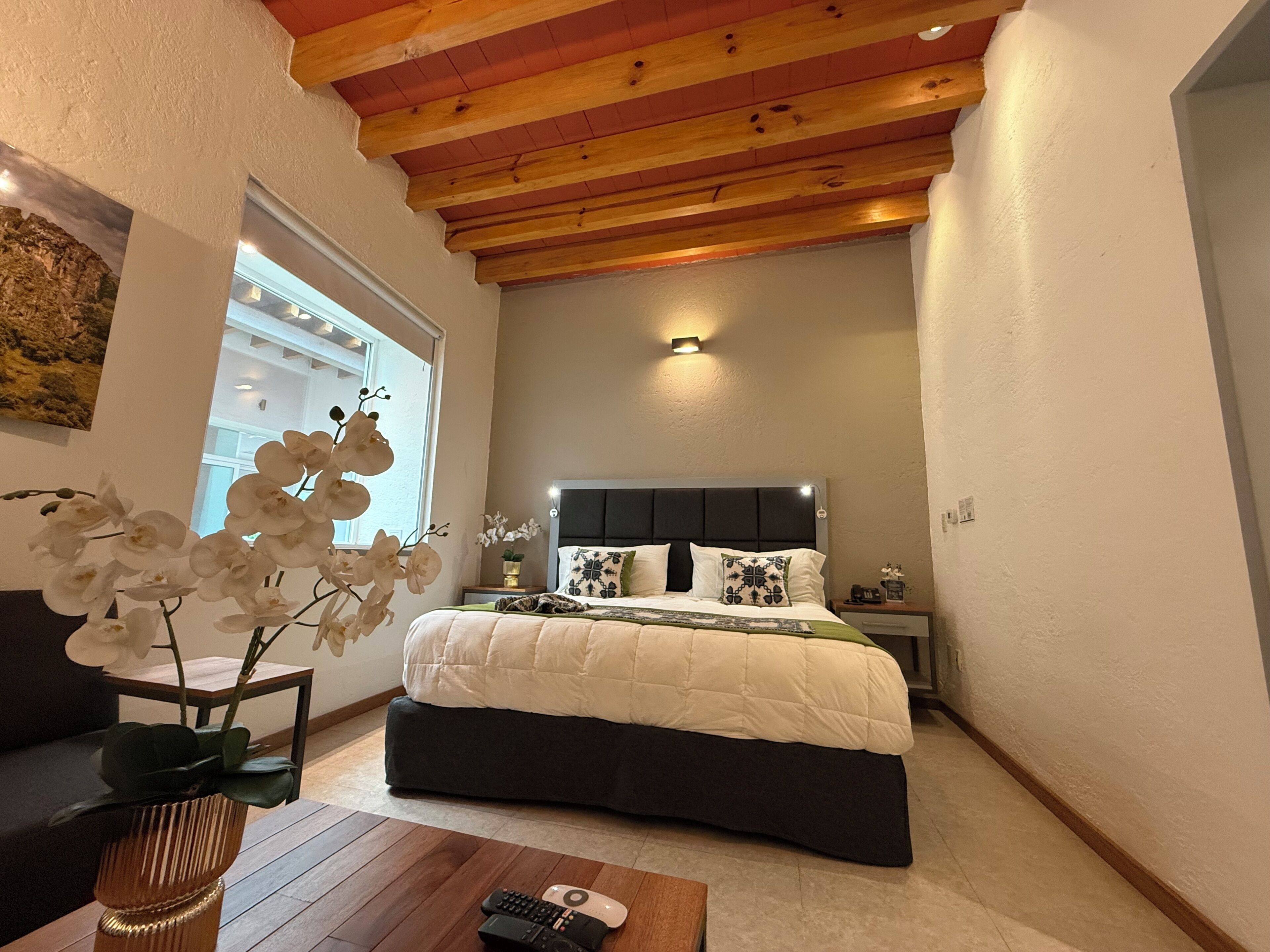 Un dormitorio con cama, mesita de noche, lámpara y ventana.