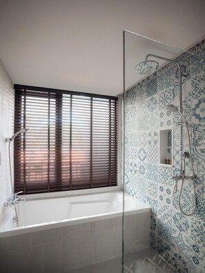 A modern bathroom with a bathtub, shower, and patterned tiles. - Burirattana (Chiang Mai)