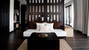 A modern bedroom with a dark wooden partition, a white sofa, and a black coffee table. - Burirattana (Chiang Mai)