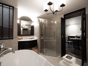 Een moderne badkamer met een vrijstaand bad, een douche met glazen wanden en een wastafel met een grote spiegel.