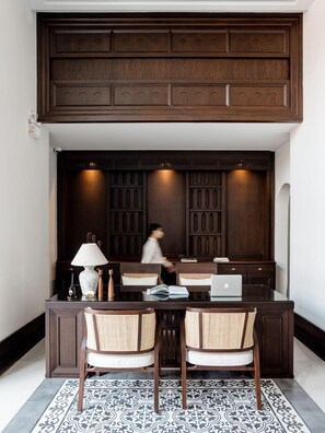 A dining area with a dark wooden table, two wicker chairs, a laptop, and a lamp. - Burirattana (Chiang Mai)