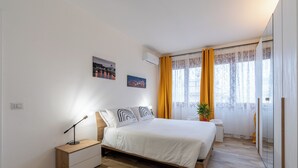 Ein modernes Schlafzimmer mit einem hölzernen Bett, Nachttischen, einem Beistelltisch und einer Topfpflanze.