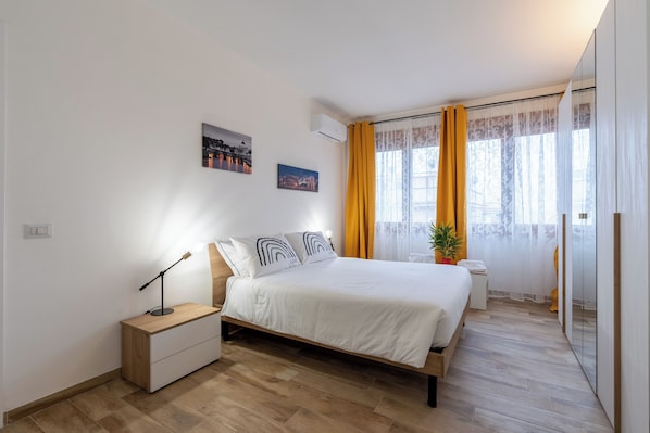 Un dormitorio moderno con una cama de madera, mesitas de noche y una planta en maceta.