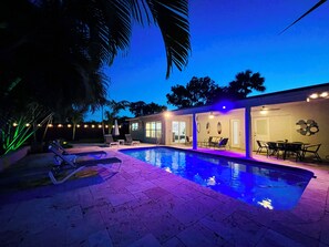 A modern house with a swimming pool, outdoor seating, and a patio area.