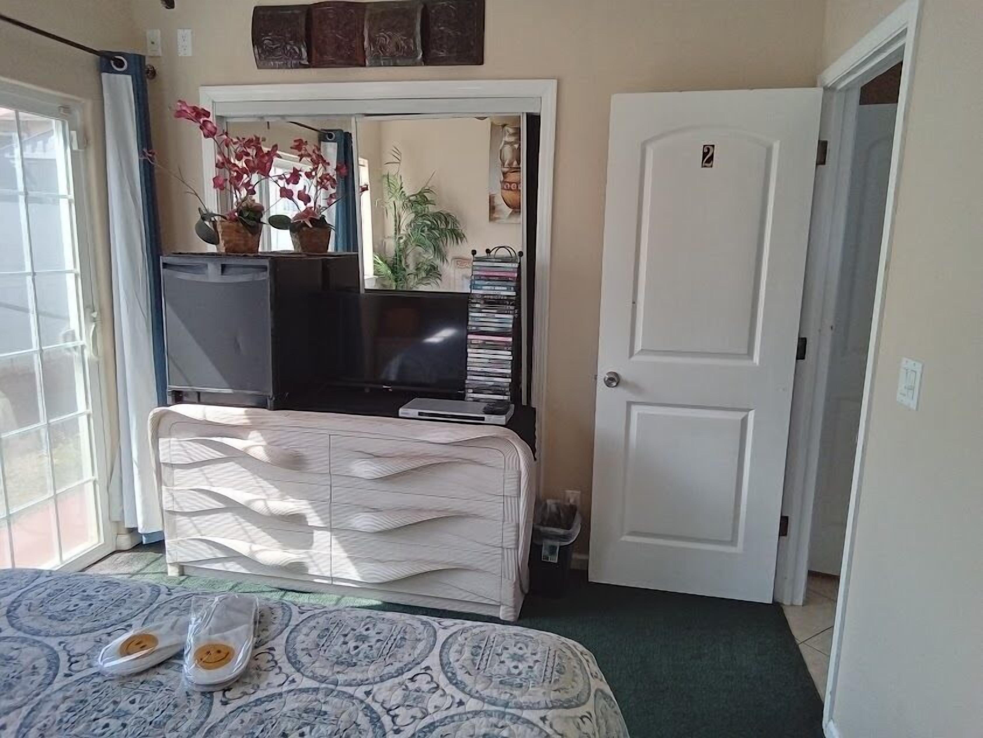 Un dormitorio con cama, cómoda, televisor y puerta.