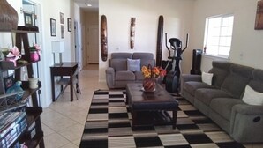 A living room with a checkered rug, a sofa, a coffee table, and a bookshelf. - Robbins Estate (Wailuku)