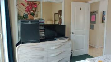 A bedroom with a white dresser, a television on top, and a door labeled "LINDY".