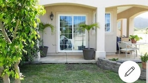 A house with a patio area, a large sliding glass door, and potted plants. - Robbins Estate (Wailuku)