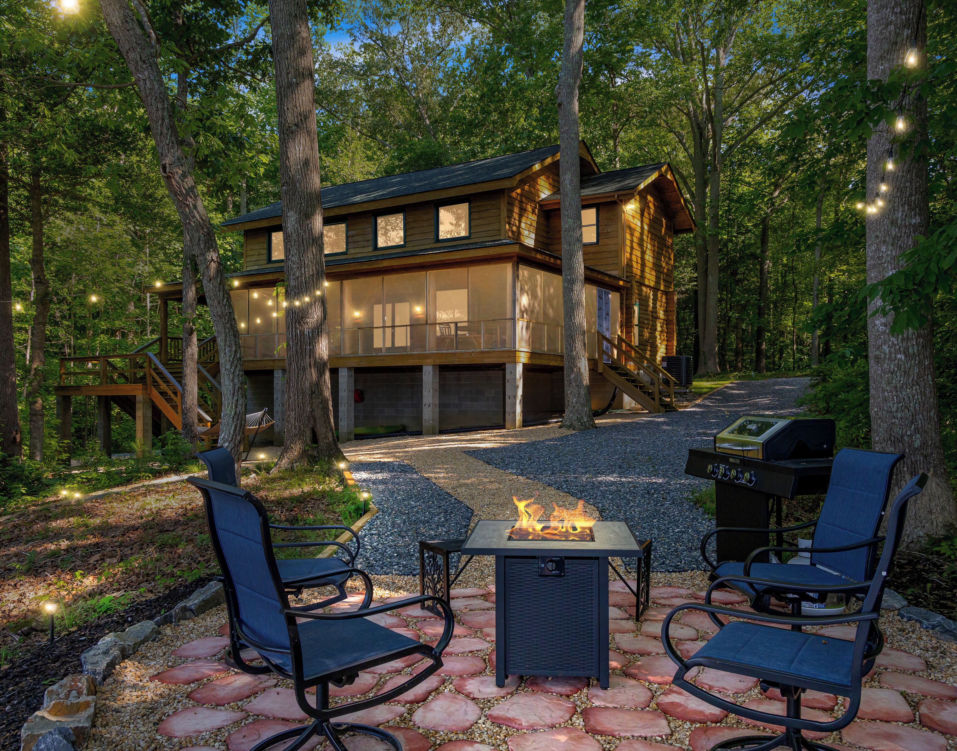 A wooden cabin with a deck, outdoor seating, and a fire feature.