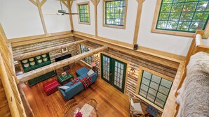 A spacious loft-style room with a high ceiling, wooden beams, and large windows. - Waterfront Cabin! Dock, Crab, Paddle, Kayak, Outdoor Movie, Karaoke, and More! (Heathsville)